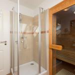Dusche mit Glaswand und Sauna mit Holzbank