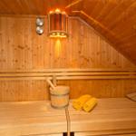 Sauna mit Holzbank, Eimer und gelben Handtüchern. Decke und Wände aus Holz.