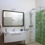 Badezimmer mit Dusche, Waschbecken und Spiegel.