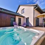 Haus mit Whirlpool, Terrasse und Sitzgelegenheiten unter einem Sonnenschutz.