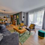 Wohnbereich mit Sofa, Sesseln und Kamin. Durchgang zur Küche und Terrasse.