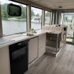 Küche mit Fenstern zum Wasser und Steuerstand mit Ledersitz.