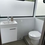 Badezimmer mit Waschbecken, Toilette und großem Fenster.