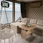 Wohnbereich mit Sofa, Hängesessel und Blick auf Wasser.