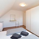 Schlafzimmer mit Babybett, Bett und Kleiderschrank. Wandregal und Stuhl sind vorhanden.