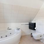 Dusche mit Badewanne, Toilette und schwarzer Schrankwand.