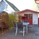 Terrasse mit Tisch, Stühlen, Wickerbank und kleinem Holzhaus.