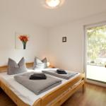 Schlafzimmer mit Holzbett, Nachttisch und Fenster. Wandbild und Holztür sichtbar.