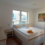 Schlafzimmer mit Doppelbett, Fenster und Wandbild.