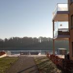 Wohnung mit Balkon, Blick auf Fluss und Uferweg mit Bänken.