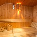 Sauna mit Holzbank, Holzschale und Wandthermometer.