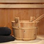 Holzbadewanne mit Besen und Handtuch in Sauna