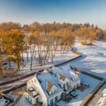 Wohnhaus mit Schneebedecktem Dach und Gartenbereich in winterlicher Umgebung.