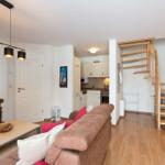 Wohnung mit Wohnzimmer, Küche und Holztreppe zur oberen Etage.
