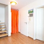 Haus mit Holztreppe, orangefarbener Vorhang und weißen Türen.