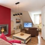 Wohnzimmer mit Kamin, Sofa, Fernseher und Holzboden.