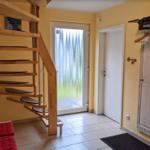Hausflur mit Holztreppe, Glastür und Kleiderständer