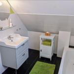 Badezimmer mit Waschbecken, Badewanne und grünen Handtüchern.