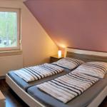 Schlafzimmer mit Doppelbett, Fenster und Nachttischen mit Lampen.