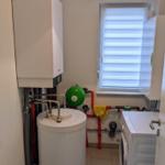 Heizungsraum mit Boiler, Waschmaschine und Fenster mit Jalousie.