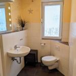 Badezimmer mit Waschbecken, Toilette und Fenster mit Bambusmuster.
