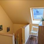 Haus mit Treppe, Dachfenster und kleiner Sitzgelegenheit