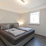 Schlafzimmer mit Doppelbett, Fenster und Nachttisch mit Lampe.