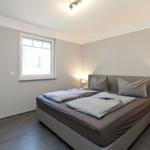 Schlafzimmer mit Doppelbett, Fenster und Nachttischen mit Lampen.