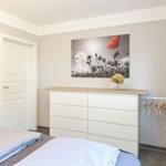 Schlafzimmer mit Bett, Kleiderschrank und Wandbild mit Mohnblume.