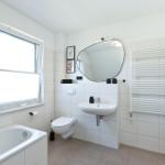 Badezimmer mit Badewanne, Waschbecken, Toilette und Heizkörper.