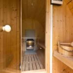 Sauna mit Holzwand, Sitzbank und Holztonne mit Löffel
