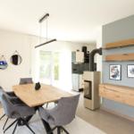 Essbereich mit Holztisch, grauen Stühlen und moderner Einbauküche.