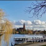 Uferpromenade mit Booten und Kirche im Hintergrund