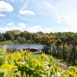 Garten mit Blick auf einen See und grüne Bäume im Hintergrund.