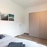 Schlafzimmer mit Bett, Kleiderschrank und Wandbildern