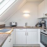 Kitchen with skylight, white cabinets, and stainless steel appliances.