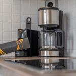 Coffee machine with glass carafe and Nespresso capsules on kitchen countertop.