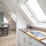 Kitchen with worktop and dining area under sloped ceilings with windows.