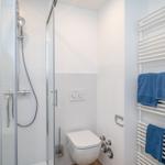 Shower with shower head, toilet, and towel warmer with towels.