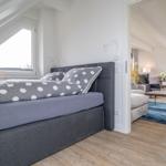 Bedroom with sloped ceiling, double bed, and view into living area.
