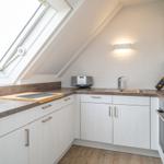 Kitchen with sloped ceiling, window, countertops, and appliances.