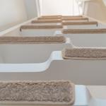 Staircase with white steps and beige carpet strips
