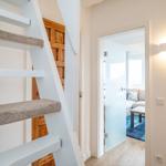 Staircase with wooden door and view into living room with sofa and rug