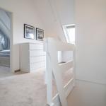 Bedroom with double bed and window. Adjacent room with white bunk bed and dresser.