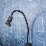 Desk lamp in front of blue wallpaper with ship blueprints