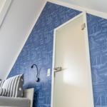 Bedroom with blue sailboat wallpaper, bed, and door.