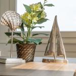 Wooden table with decorative items: seashell, sailboat, and flower pot.