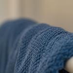 A blue towel on a white towel rack in a bathroom.