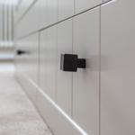 Black handle on a white cabinet with vertical panels.