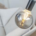 A large bulb with visible filaments reflects the room.
